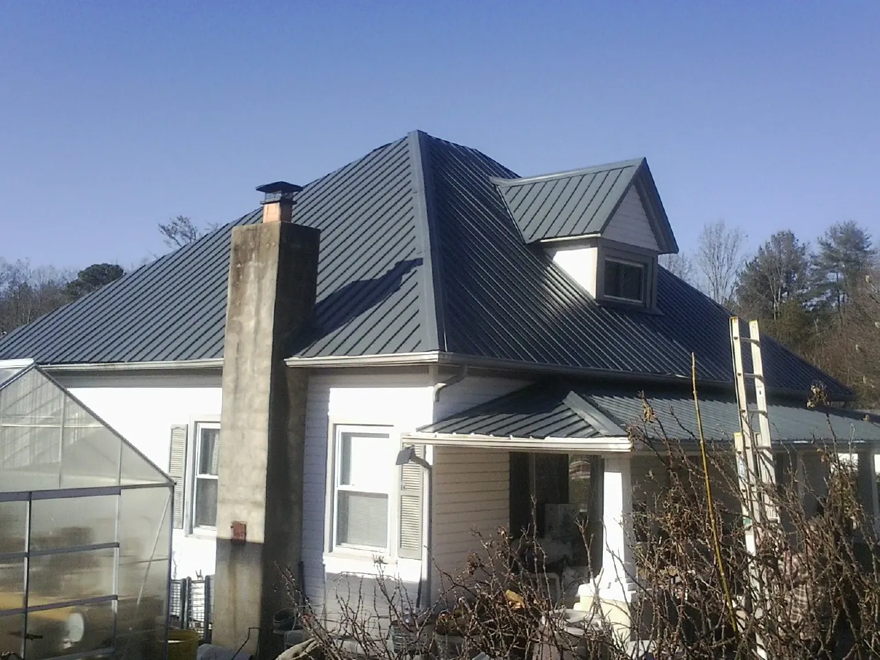 Dark blue standing seam metal roof on a white farmhouse with dormer — Slate & Tile Roof Repair by Roofing Brothers in Zumbrota