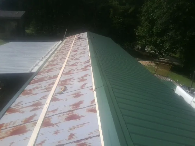 Old rusted panels beside newly installed green metal roofing — Wind Damage Roof Repair by Roofing Brothers in Zumbrota