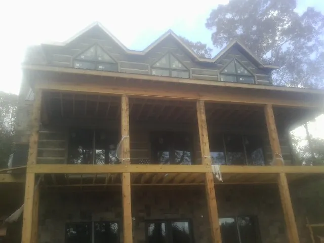 Dormers and porch framing on a large log home under construction — Roof Coating work by our crew in Zumbrota