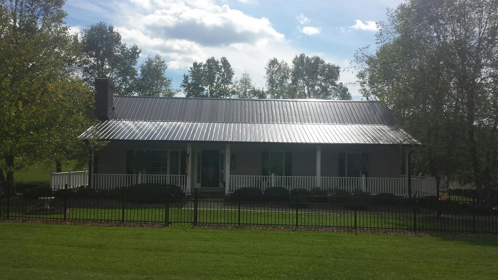 Gray metal roof on a brick ranch with a full width front porch — Gutter Guard Installation work by our crew in Zumbrota