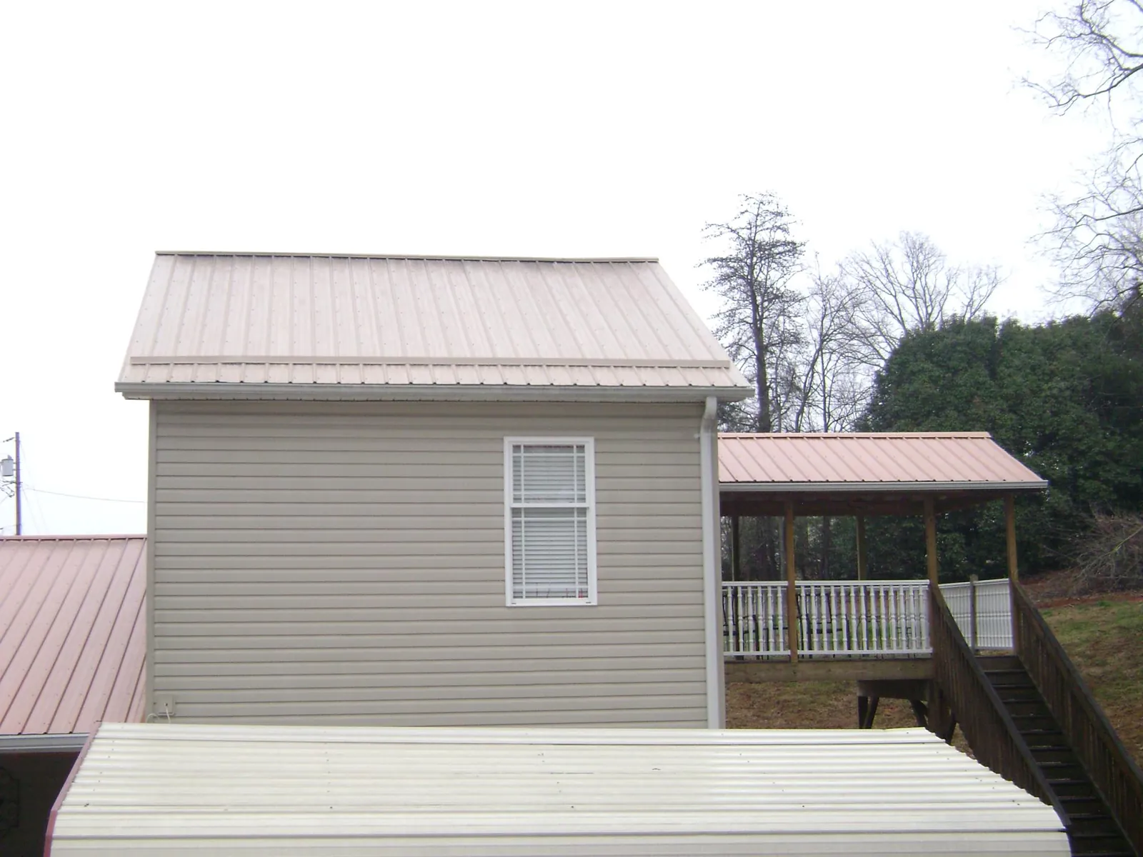 Tan metal roofs on a two story addition and attached porch, from a Roof Replacement job in Zumbrota