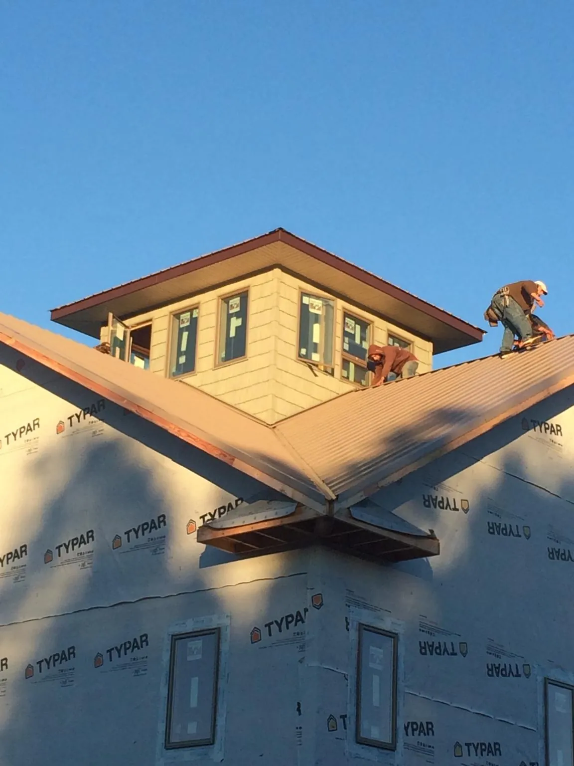 Roofers working around a rooftop cupola on a new metal roof at sunset — Roof Waterproofing in Zumbrota by Roofing Brothers